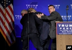 Secret Service agents rush Republican presidential candidate Donald Trump off the stage at a campaign rally in Reno, Nev., Nov. 5, 2016.