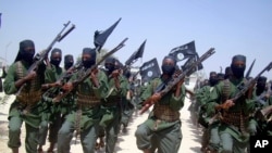 FILE - Al-Shabab fighters are seen marching with their weapons during exercises on the outskirts of Mogadishu, Somalia. Some al-Shabab members are fleeing to the capital and to areas near the border with Kenya because they were overpowered in the region of Middle Juba.