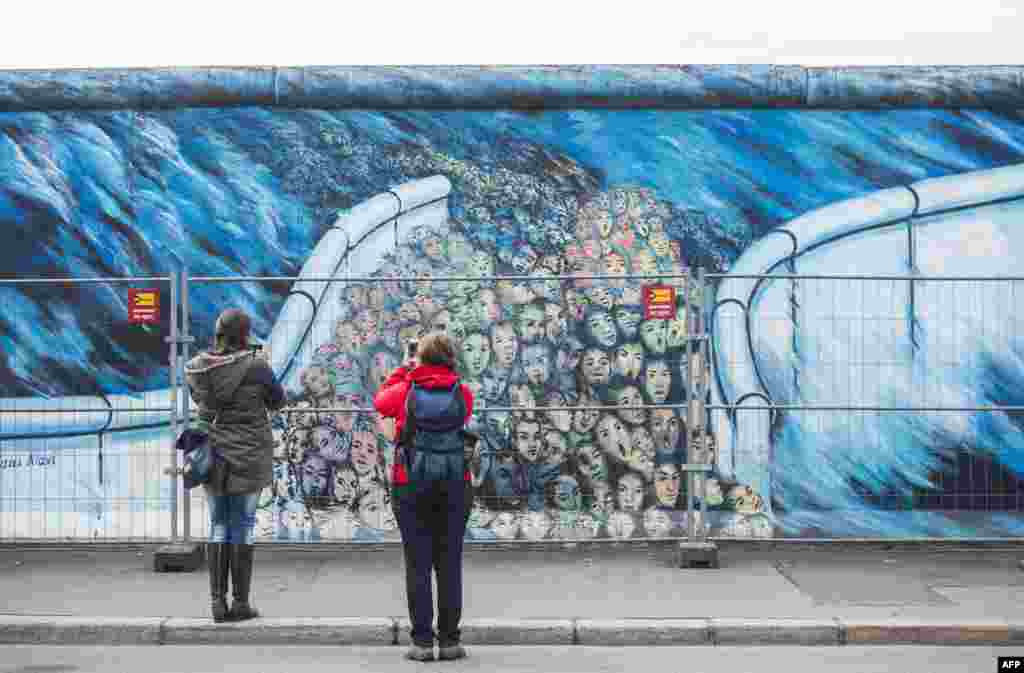 A temporary fence protects wall paintings on the East Side Gallery, a much-visited stretch of the Berlin wall, while graffiti-cleaning work is underway in Berlin, Germany. The city of Berlin has decided to erect a 80-cm-high permanent barrier to discourage people from defacing the works made by artists who decorated the yet untouched east side with artwork and political statements after the wall was taken down in 1989-1990.
