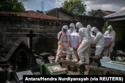 Petugas Pemkot mengenakan alat pelindung diri (APD) membawa peti jenazah korban COVID-19 di Badran, Yogyakarta, 22 Juni 2021. (Foto: Antara/Hendra Nurdiyansyah via Reuters)