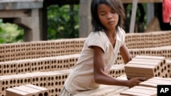 A Cambodian girl prepares bricks to dry under the sun light at a brick factory in Chheuteal village, Kandal province, some 27 kilometers (17 miles) north of Phnom Penh, Cambodia, Monday, May 2, 2011. 