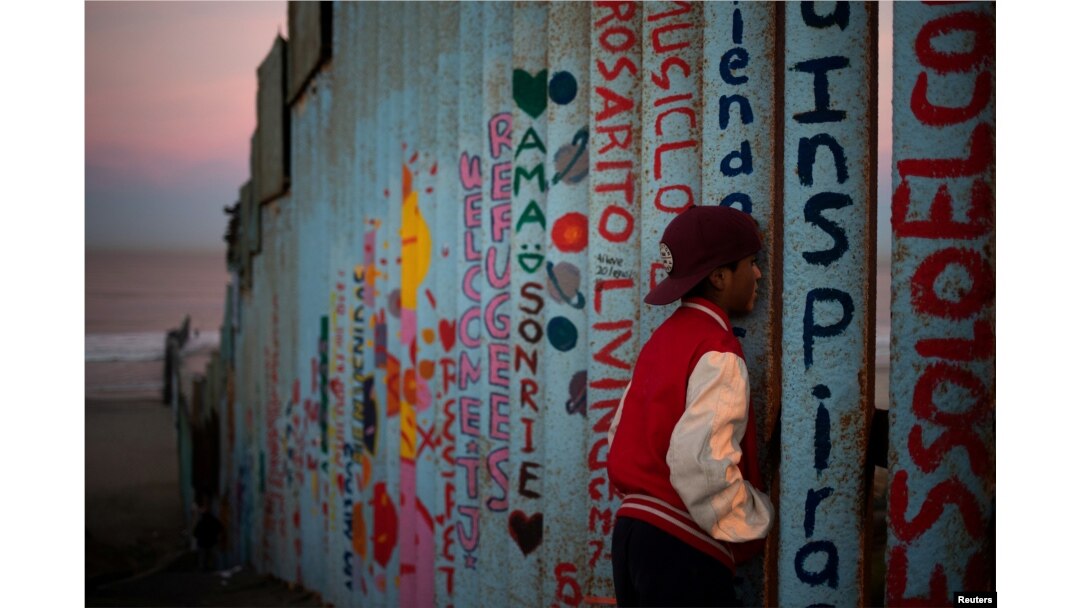 Angel (13), migran dari Honduras, yang bergabung dengan kafilah migran menuju AS, mengamati Amerika dari balik pagar perbatasan di Tijuana, Meksiko, 15 November 2018. (Foto: dok).