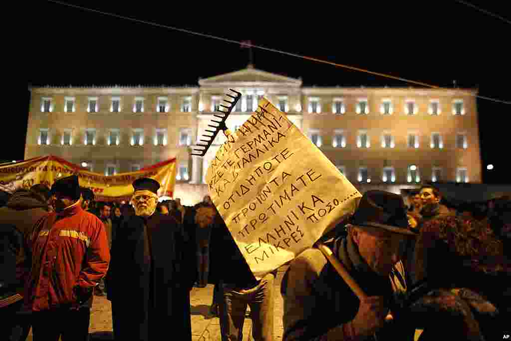 A protester with a placard placed on on a rake chats with another protester at Syntagma Square in front of the Greek parliament, in central Athens, on February 19, 2012. (AP)