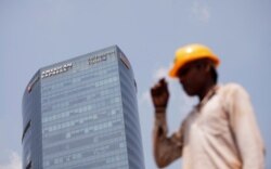 Seorang pekerja mengenakan topi pelindung saat melintas di depan gedung American Express di Gurugram, di pinggiran New Delhi, India, 8 September 2017. (Foto: Reuters)