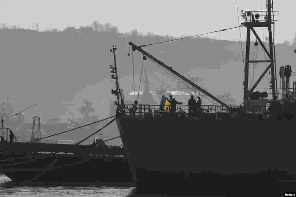 Ukrainian Navy sailors raise the Ukrainian flag on the Ukrainian navy command ship Slavutych as it is blocked by two Russian ships at the Crimean port of Sevastopol, March 21, 2014. 