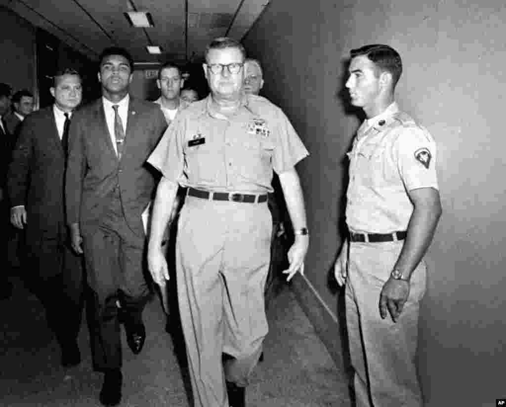 FILE - Heavyweight boxing champion Muhammad Ali is escorted from the Armed Forces Examining and Entrance Station in Houston by Lt. Col. J. Edwin McKee, after Ali refused Army induction, April 28, 1967. Ali died at age 74, June 3, 2016.