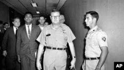 FILE - Heavyweight boxing champion Muhammad Ali is escorted from the Armed Forces Examining and Entrance Station in Houston by Lt. Col. J. Edwin McKee, after Ali refused Army induction, April 28, 1967. Ali died at age 74, June 3, 2016.