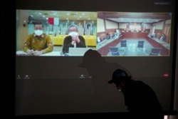 Live streaming sidang mantan Mensos Juliari Batubara (kiri) yang diselenggarakan secara virtual di tengah pandemi COVID-19 di Gedung KPK, Jakarta, 23 Agustus 2021. (AP Photo/Dita Alangkara)