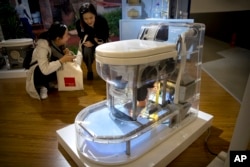 Visitors look at a model of a self-contained toilet at the Reinvented Toilet Expo in Beijing, Tuesday, Nov. 6, 2018.