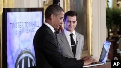 President Barack Obama types during his live-tweet as Twitter co-founder and Executive Chairman Jack Dorsey looks on during the first-ever Twitter Town Hall, July 6, 2011, in the East Room of the White House