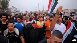 Manifestantes levantan la bandera nacional durante una protesta demandando mejores servicios públicos y trabajos en Basra, Iraq, el 11 de septiembre del 2018 
