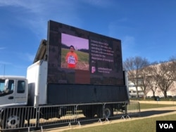 A large-screen TV showing young immigrants' stories is part of Dream Act Central, a space on the National Mall in Washington where immigration activists are pushing for legislative action to replace DACA, Dec. 13, 2017. (A. Barros/VOA)