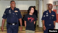 FILE - Activist Adam Adli is escorted by police at a courthouse in Kuala Lumpur.