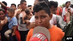 A Honduran migrant boy taking part in a caravan heading to the US, cries as he waits on the Guatemala-Mexico border bridge, in Ciudad Tecun Uman, Guatemala, on Oct. 20, 2018.