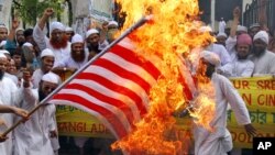 Manifestantes revoltosos contra o filme de Sam Bacile, queimam bandeira americana no Bangladesh