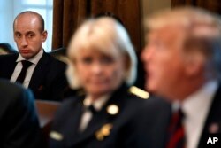 White House senior adviser Stephen Miller, left, listens listens as President Donald Trump, at right, speaks during a roundtable discussion on border security with local leaders, Jan. 11, 2019, in the Cabinet Room of the White House in Washington.