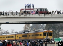 Firefighters stand on their truck and salute along with other attendants on an overpass as the train carrying the body of former president George H.W. Bush travels past on the way to Bush's final internment Dec. 6, 2018.