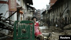 Une femme est assise sur les ruines après le passage du typhon Nepartak qui a balayé le comté de Minqing dans la province du Fujian, en Chine, 10 juillet, 2016. REUTERS / Stringer REUTERS 