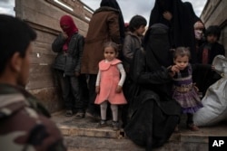 Women and children exit the back of a truck to be screened by U.S.-backed Syrian Democratic Forces (SDF) after being evacuated out of the last territory held by Islamic State militants, in the desert outside Baghouz, Syria, Feb. 27, 2019.