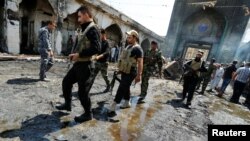 Shi'ite fighters from Saraya al-Salam, who are loyal to radical cleric Muqtada al-Sadr, gather at site of a suicide attack at the entrance of the Shi'ite Mausoleum of Sayid Mohammed bin Ali al-Hadi in Balad, north of Baghdad, Iraq, July 8, 2016. 