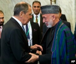 Russian Foreign Minister Sergey Lavrov, left, and former Afghan President Hamid Karzai greet each other prior to their meeting in Moscow, May 28, 2019.