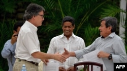 The head of the Colombian government delegation for the peace talks with the ELN guerrillas Gustavo Bell, left, and The chief negotiator of Colombia's last rebel group, the National Liberation Army (ELN), Pablo Beltran, shake hands during the sixth round of peace talks in Havana, Aug. 1, 2018.