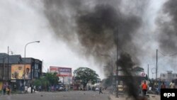 Quelques personnes marchent à proximité d'un pneu brûlé par des manifestants dans la rue dans la capitale Kinshasa, RDC, 19 janvier 2015.epa/ STR