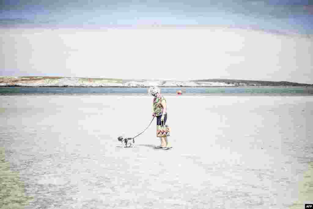 An elderly woman walks her dog in the empty Main Beach in Langebaan, South Africa.&nbsp;President Cyril Ramaphosa announced new lockdown measures to limit the spread of COVID-19.&nbsp;