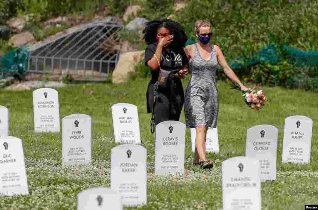 People walk among an art installation of headstones bearing the names of people killed by police near the site of the arrest of George Floyd, who died while in police custody, in Minneapolis, Minnesota, June 6, 2020.