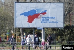 A billboard, which promotes the construction of a bridge across the Kerch Strait to the Krasnodar region, is displayed on a street in Kerch, Crimea, April 5, 2016. The board reads: "Crimean spring. We build bridges."