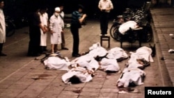 FILE: Medical workers at Beijing's Fuxingmen Hospital look at bodies of protesters killed by soldiers around Tiananmen Square on June 4, 1989.