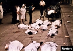 FILE - Medical workers at Beijing's Fuxingmen Hospital look at bodies of protesters killed by soldiers around Tiananmen Square on June 4, 1989.