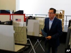 FILE - Gov. Dannel P. Malloy prepares to submit his ballot for the primary election at a polling place in Hartford, Connecticut, Aug. 14, 2018.