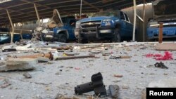 Police vehicles are parked next to debris in the Anbar province town of Hit, Iraq, Oct. 6, 2014. 