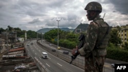FILE - A Brazilian army soldier stands guard over the "Linha Amarela" (yellow line) road during a joint operation at "Cidade de Deus" (City of God) favela in Rio de Janeiro, Feb. 07, 2018. 