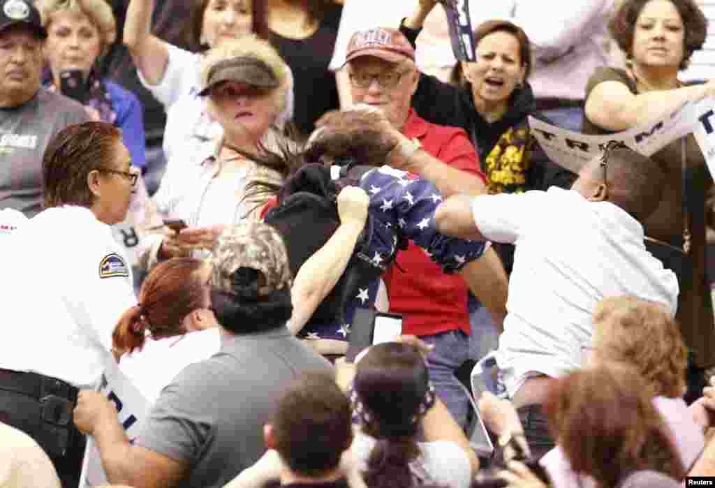 A member of the audience (R) throws a punch at a protester as Republican Presidential candidate Donald Trump speaks during a campaign event in Tucson, Arizona, March 19, 2016.
