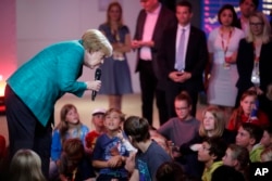 German Chancellor Angela Merkel, left, attends a news conference for children during a family event of her Christian Democratic Union party in Berlin, Sept. 17, 2017.