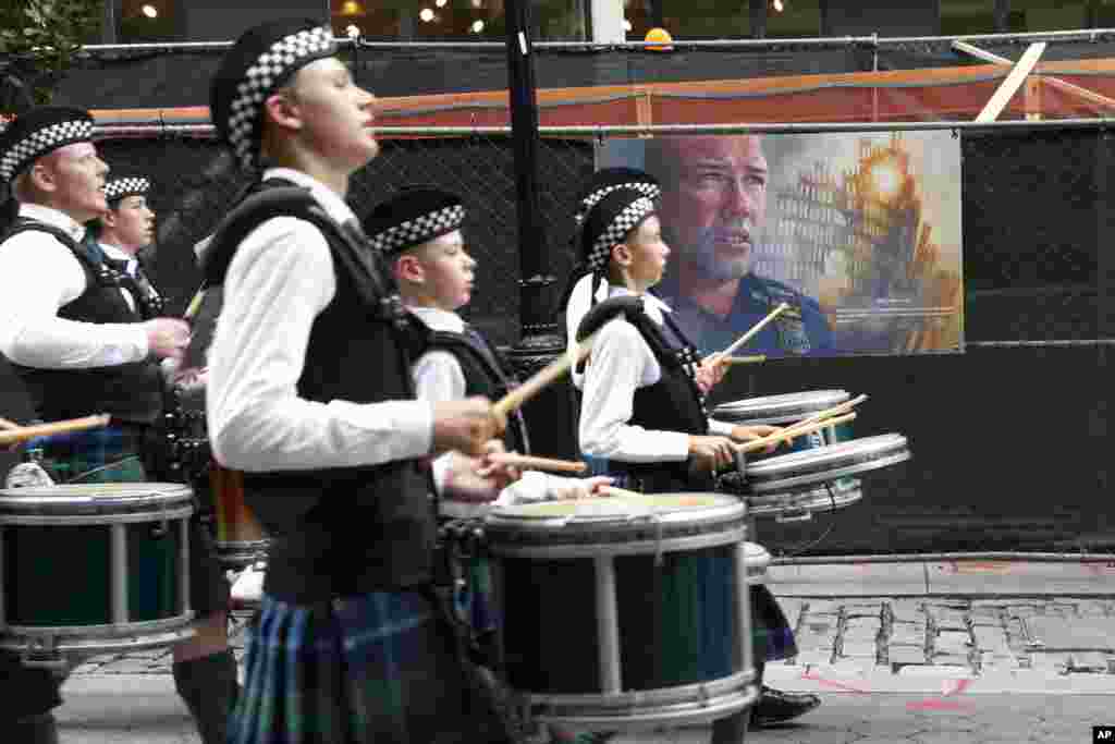 A marching band passes artwork depicting a fallen New York City police officer from Sept. 11, 2001, as they march during the NYPD Emerald Society Pipes & Drums memorial procession, in New York.