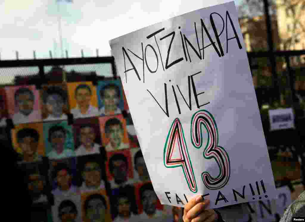 A woman holds up a sign that reads &quot;Ayotzinapa lives - 43 are missing&quot; next to pictures of the 43 missing students of Ayotzinapa College on a police fence outside the Casa Rosada Presidential Palace during a protest against the visit to Argentina by Mexico&#39;s President Enrique Pena Nieto, in Buenos Aires, Argentina.