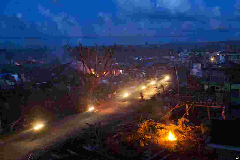 Para korban selamat bencana Topan Haiyan naik sepeda motor melalui reruntuhan kota Guiuan, Filipina yang hancur.