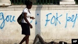 A woman walks past an unconscious man on a street just outside the quake-destroyed Presidential Palace in Port-au-Prince, Haiti, 16 Nov. 2010. The country's cholera death toll has passed 1,000 as the epidemic showed no sign of abating.