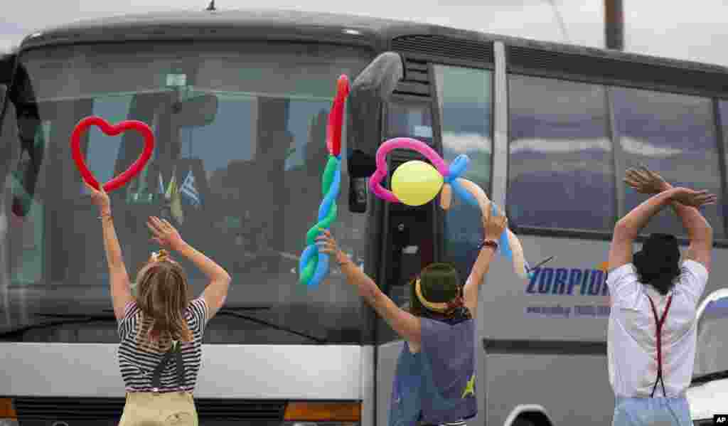 Activists, who typically entertain migrant children, greet migrants who are being evacuated from a camp near Idomeni, Greece.