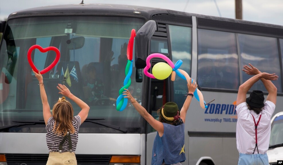 Activists, who used to entertain migrant children, greet migrants who are evacuated from a camp near Idomeni, Greece.