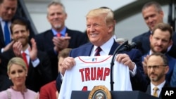 President Donald Trump shows off a Red Sox jersey presented to him during a ceremony welcoming the Boston Red Sox — the 2018 World Series champions — to the White House, May 9, 2019, in Washington.