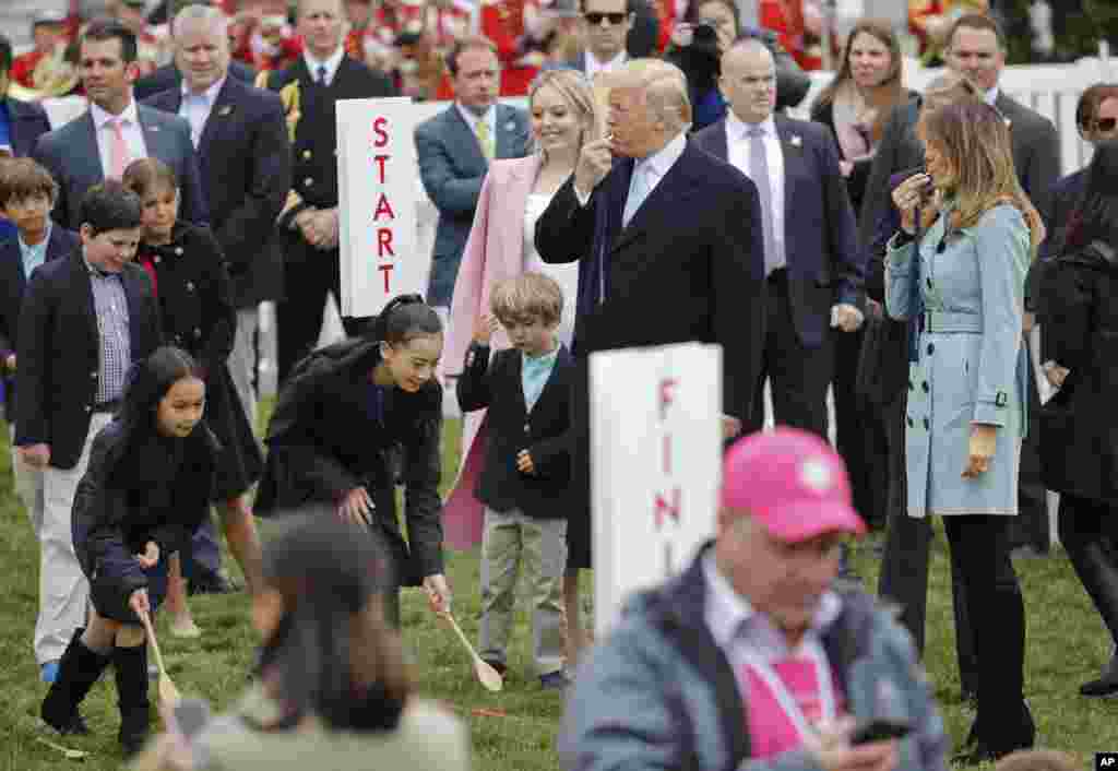 President Donald Trump, center, and first lady Melania Trump, right, blow whistles to start a race at the annual White House Easter Egg Roll on the South Lawn of the White House in Washington, Monday, April 2, 2018. (AP Photo/Pablo Martinez Monsivais)