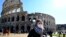 Du khách mang khẩu trang bên ngoài thắng cảnh the Colosseo ở Rome ngày 28/2/2020 giữa dịch Covid-19. (Photo by Andreas SOLARO / AFP)