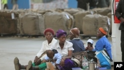 FILE - Indigenous tobacco farmers, with their children, wait to sell their tobacco, at Boka Tobacco auction floors, in Harare, Zimbabwe, May 14, 2013. 