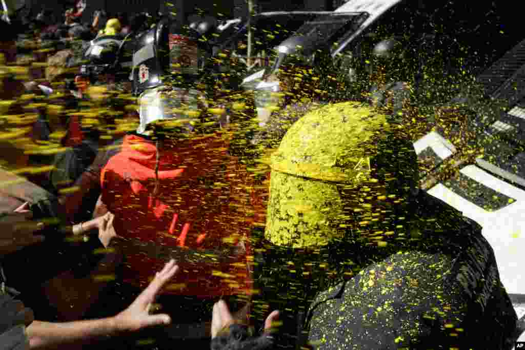 Pro-independence demonstrators throw paint at Catalan police officers during clashes in Barcelona, Spain, Sept. 29, 2018.