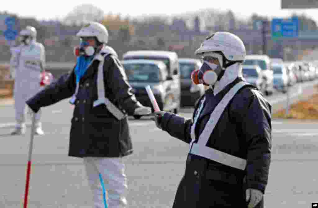 Police officers wearing respirators guide people to evacuate away from the Fukushima Daiichi nuclear plant following an evacuation order for residents who live near the plant after an explosion in Tomioka Town in Fukushima Prefecture, March 12, 2011