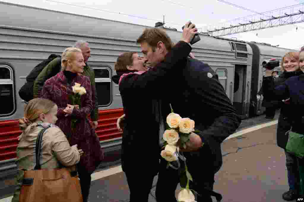 Russian opposition leader Alexei Navalny (C, R) is greeted by a supporter upon his arrival with his wife Yulia (2ndL) at a railway station in Moscow after his trial in the provincial northern city of Kirov. A court in Kirov converted his five-year sentence into a suspended term.